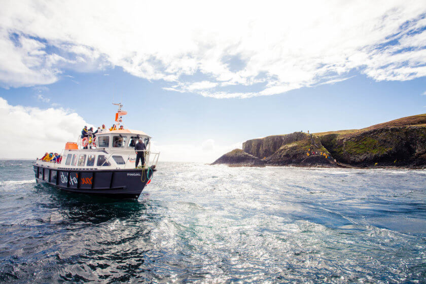 A boat from Staffa Tours off the shore of the Isle of Staffa near Fingal's Cave in Scotland.