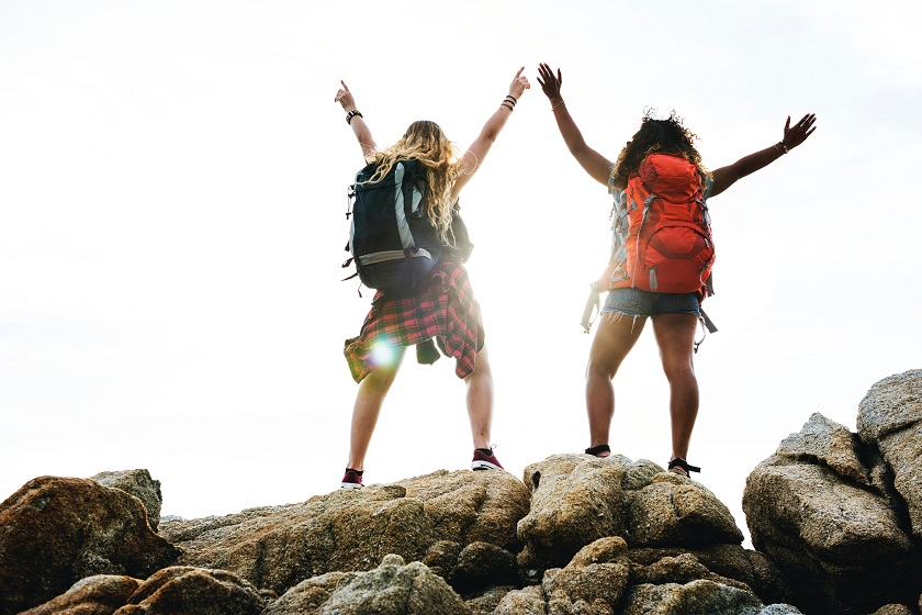 Two women with backpacks standing on a rock.